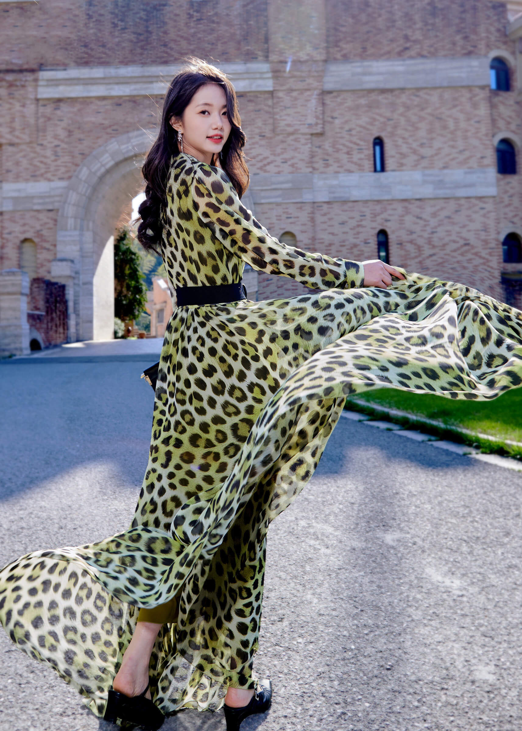 Dynamic action shot from the side, demonstrating the movement and high-quality drape of the leopard print chiffon dress as the model turns.
