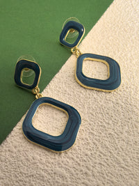 A close-up, eye-level shot of the blue enamel earrings against a two-toned background. The earrings have a shiny finish and a gold-tone base.