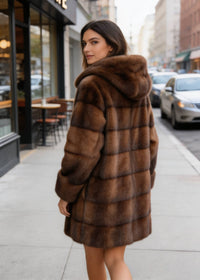 Back view of model wearing mid-length Vivian Seven brown faux fur hooded winter coat.