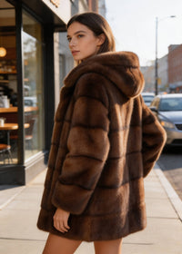 Model looking back over shoulder in Vivian Seven brown faux fur hooded winter coat on city sidewalk.