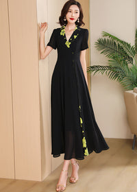 Side Pose,Side profile of a floor-length black chiffon dress showing the contrast floral print and flowing hemline.