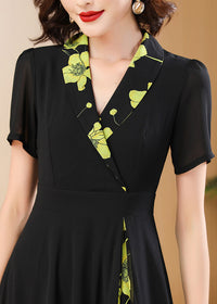 Neckline Detail,Close-up detail of the V-neckline and wrap bodice on a black dress with lime green floral embroidery-style print.