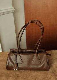 Front view of a vintage brown genuine leather handbag with soft texture and long shoulder straps