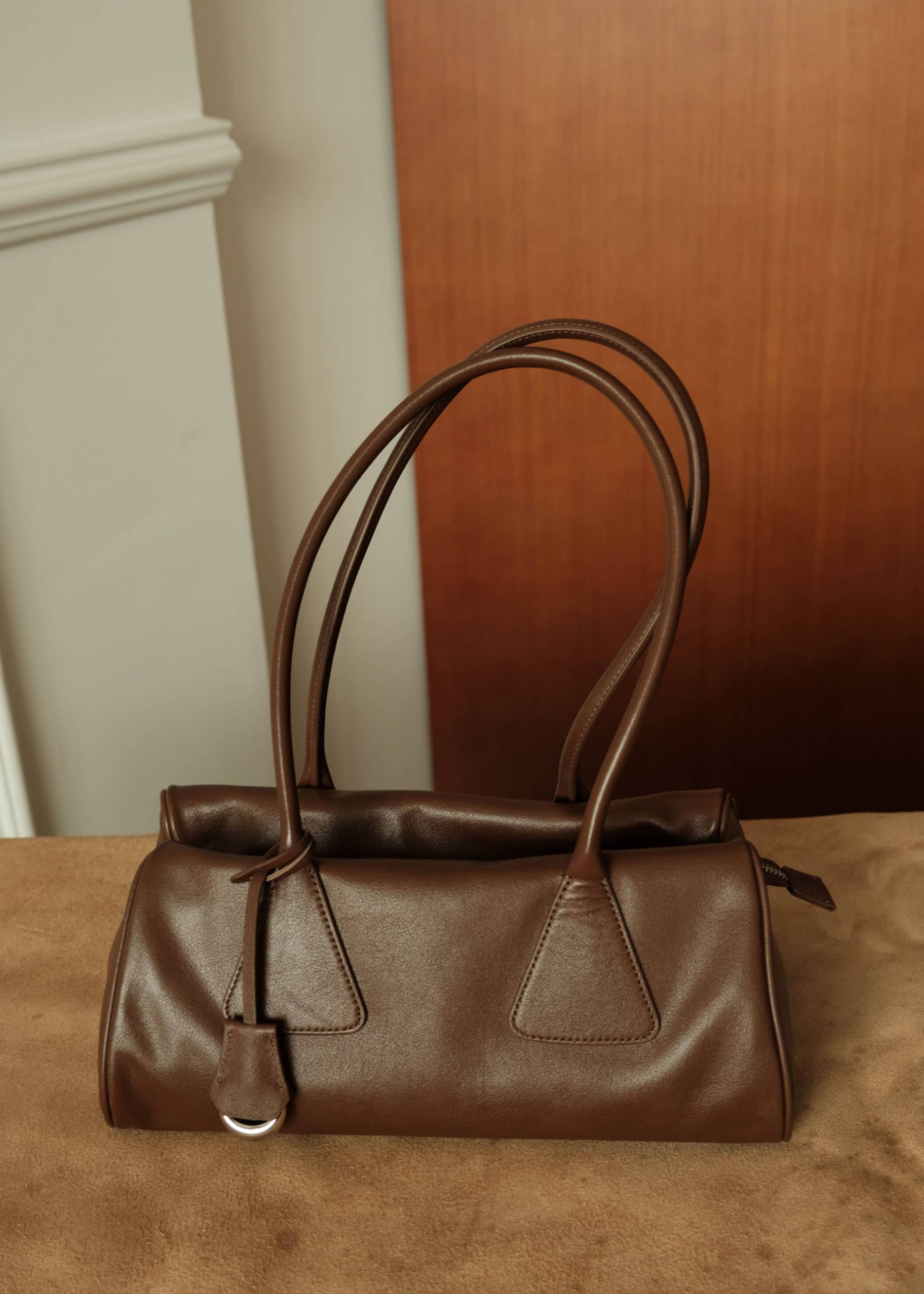 Front view of a vintage brown genuine leather handbag with soft texture and long shoulder straps