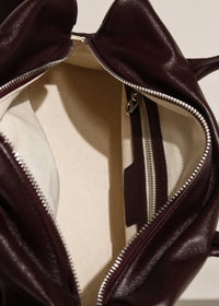 Interior view of burgundy leather handbag with cream canvas lining and inner zippered pocket