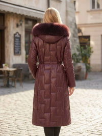 Full length back view of woman wearing burgundy Vivian Seven genuine leather puffer long down parka with fur hood