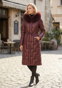 Three-quarter view of woman with hand in pocket wearing burgundy Vivian Seven genuine leather puffer long down parka