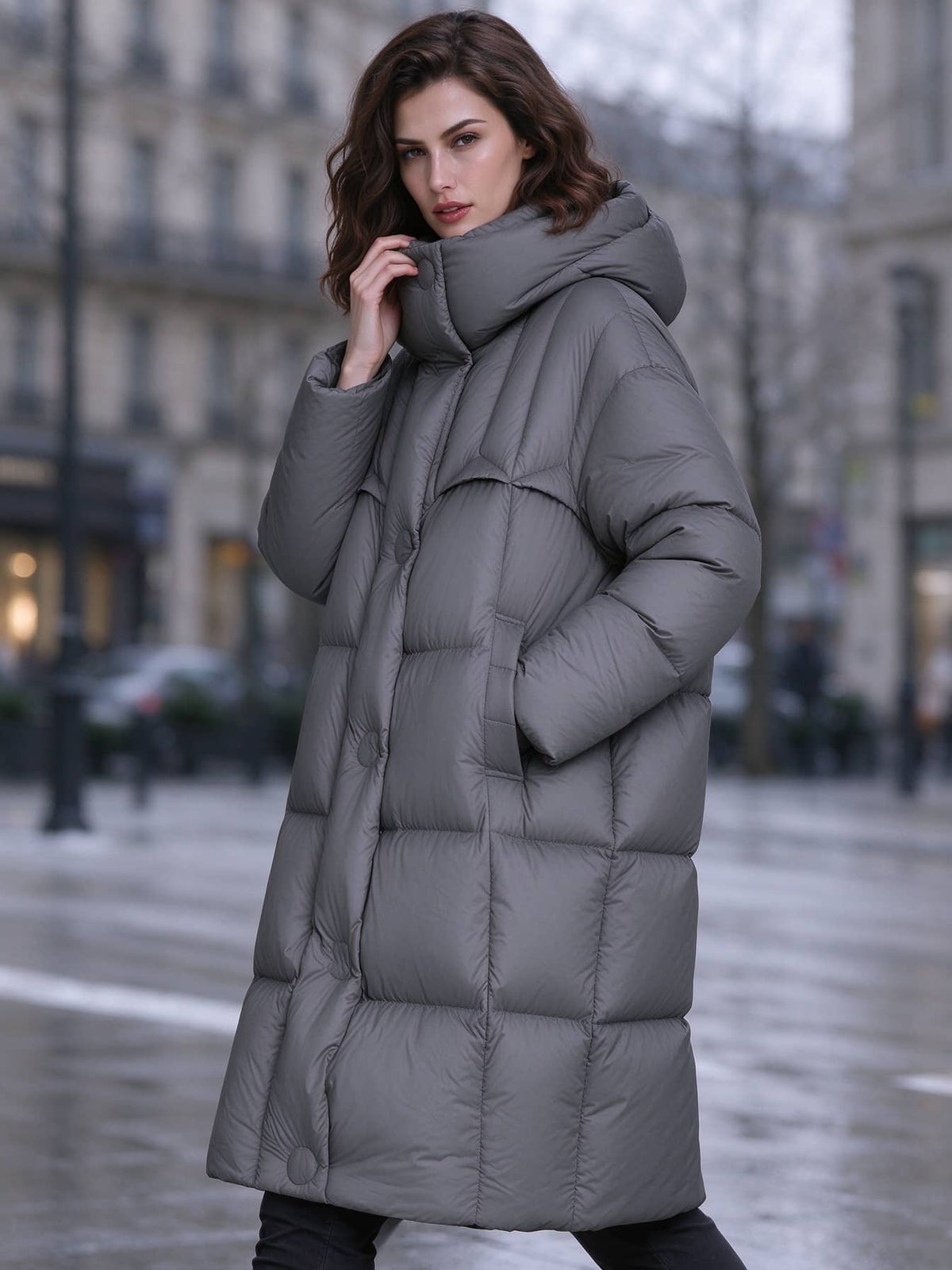 Woman holding high funnel neck collar wearing dark grey longline down puffer coat outdoors
