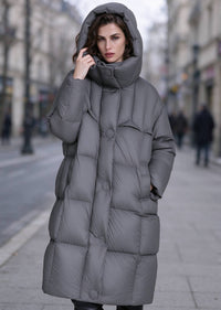 Woman with hood up wearing dark grey high funnel neck longline down puffer parka