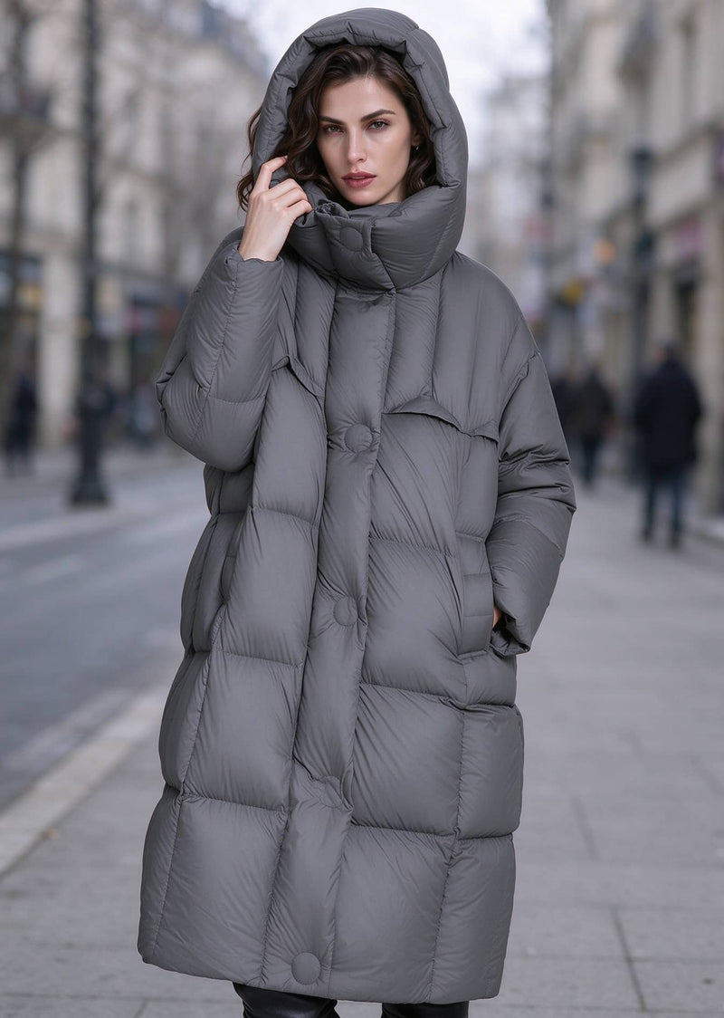 Woman with hood up wearing dark grey high funnel neck longline down puffer parka