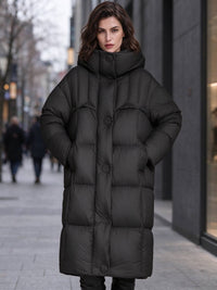 Front view of woman wearing black longline high funnel hooded down puffer parka coat