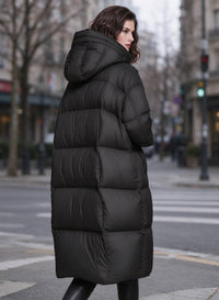 Side back profile view of woman wearing black longline quilted down puffer parka with hood