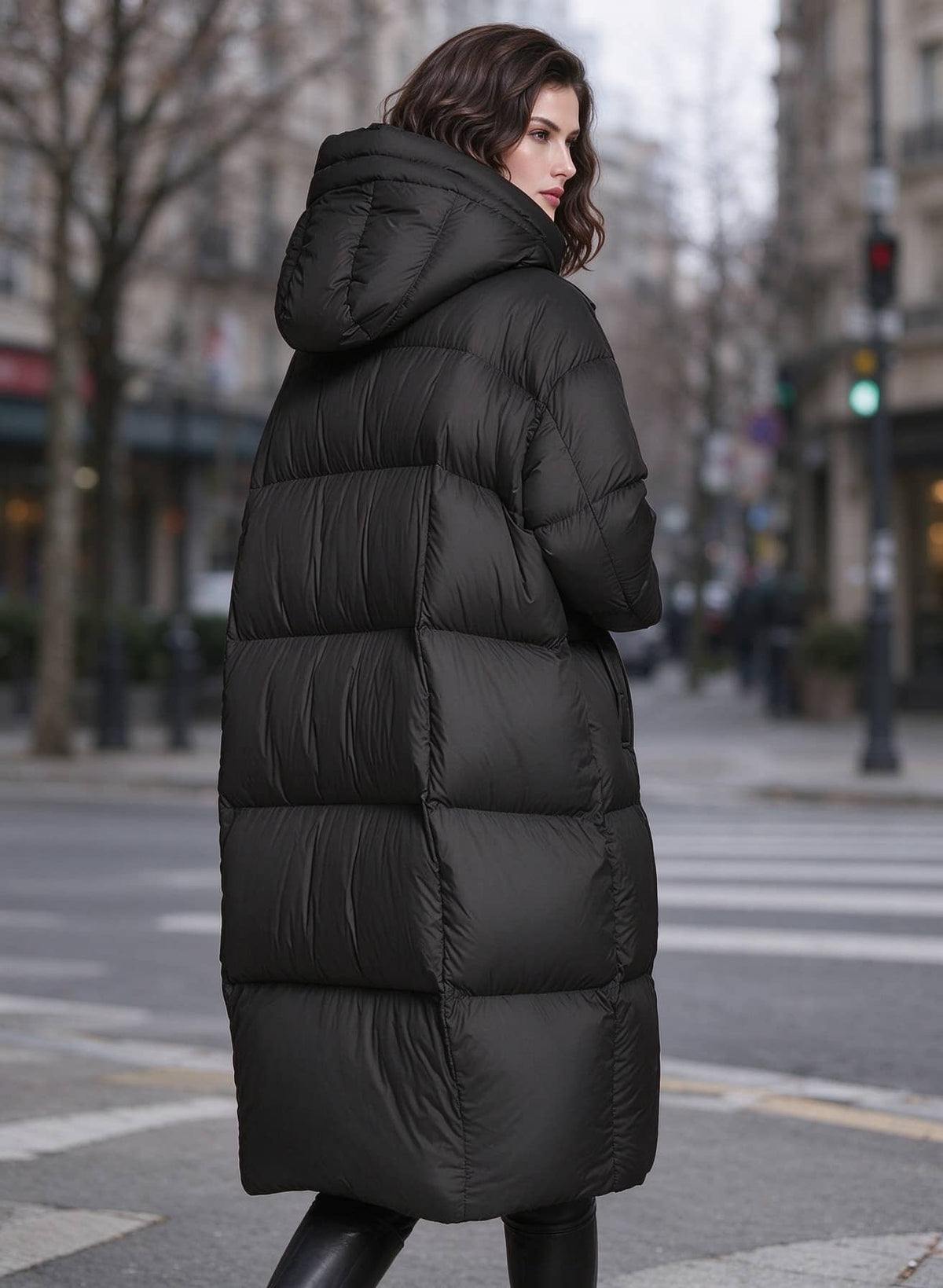 Side back profile view of woman wearing black longline quilted down puffer parka with hood
