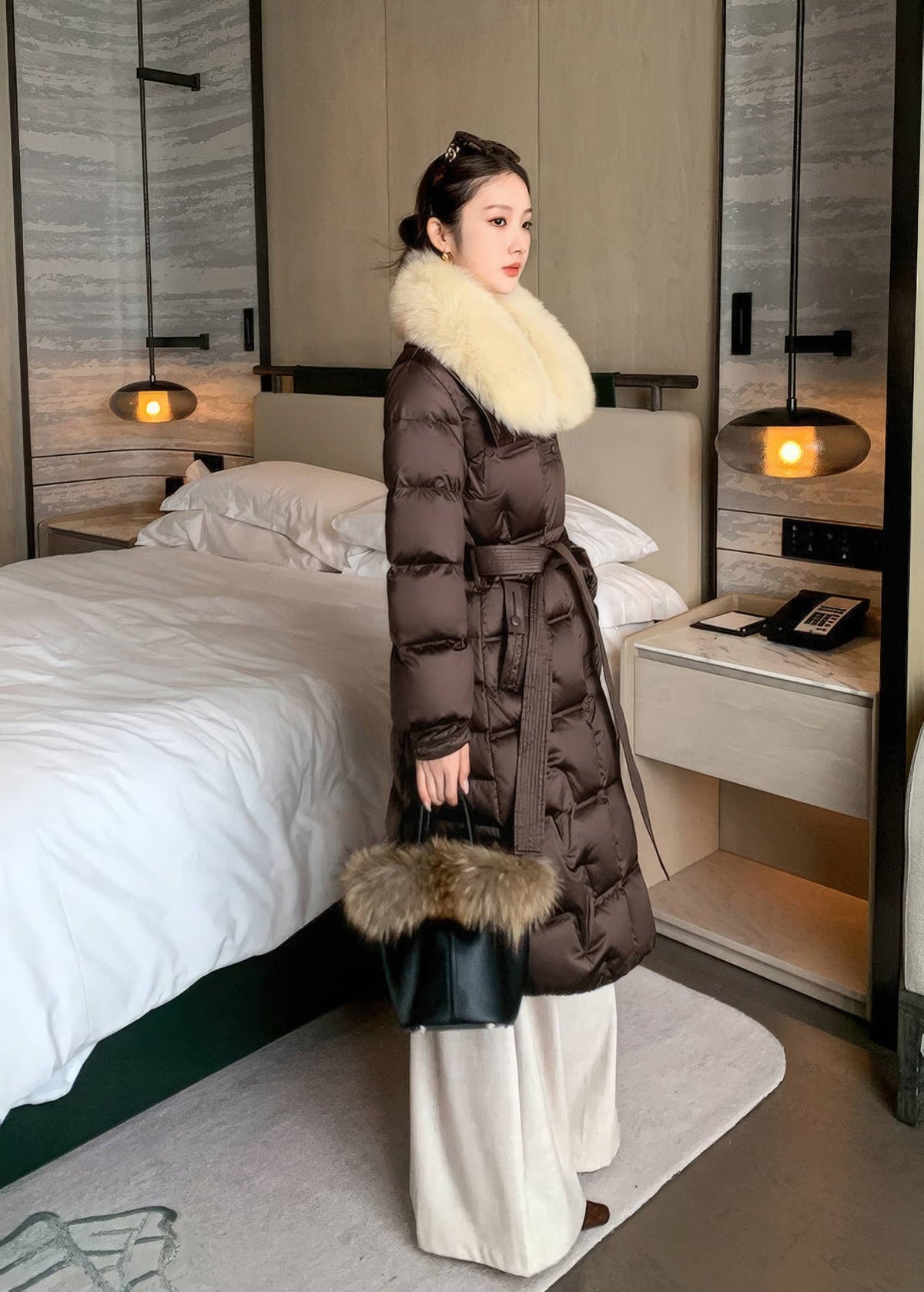 Full length side profile of woman wearing brown belted long puffer jacket with cream fur collar