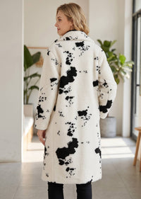 Full-length back view showing the relaxed silhouette, knee-length hem, and all-over cow spot pattern of the faux shearling coat. 