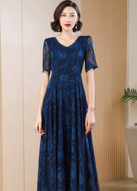 Close-up front view from the waist up of a woman wearing a navy blue V-neck maxi dress with a sheer floral burnout texture and short sleeves.