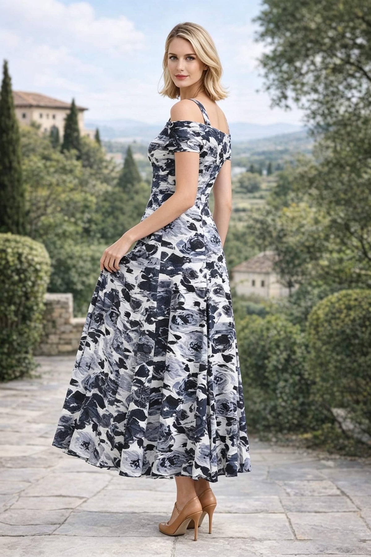 Three-quarter back view of a woman looking over her shoulder to show the back fit and design of a black and white floral print off-the-shoulder maxi dress.