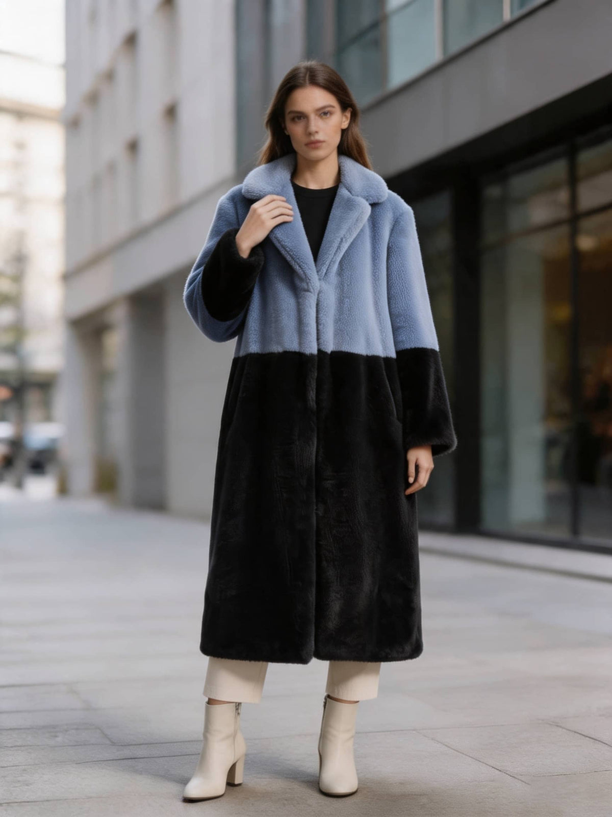 Full-length shot of a model wearing a slate blue and black color-block notch lapel faux fur long coat.