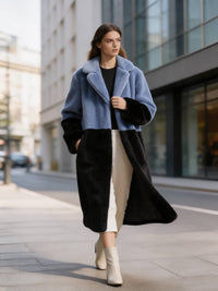 Model walking down a city street in a slate blue and black two-tone plush faux fur long coat.
