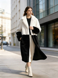 Model walking outdoors in a cream white and black two-tone notch lapel plush faux fur long coat.