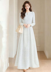 Full-length front view of a model wearing the Vivian Seven white tweed maxi dress with long sleeves and an A-line skirt, paired with a beige handbag.