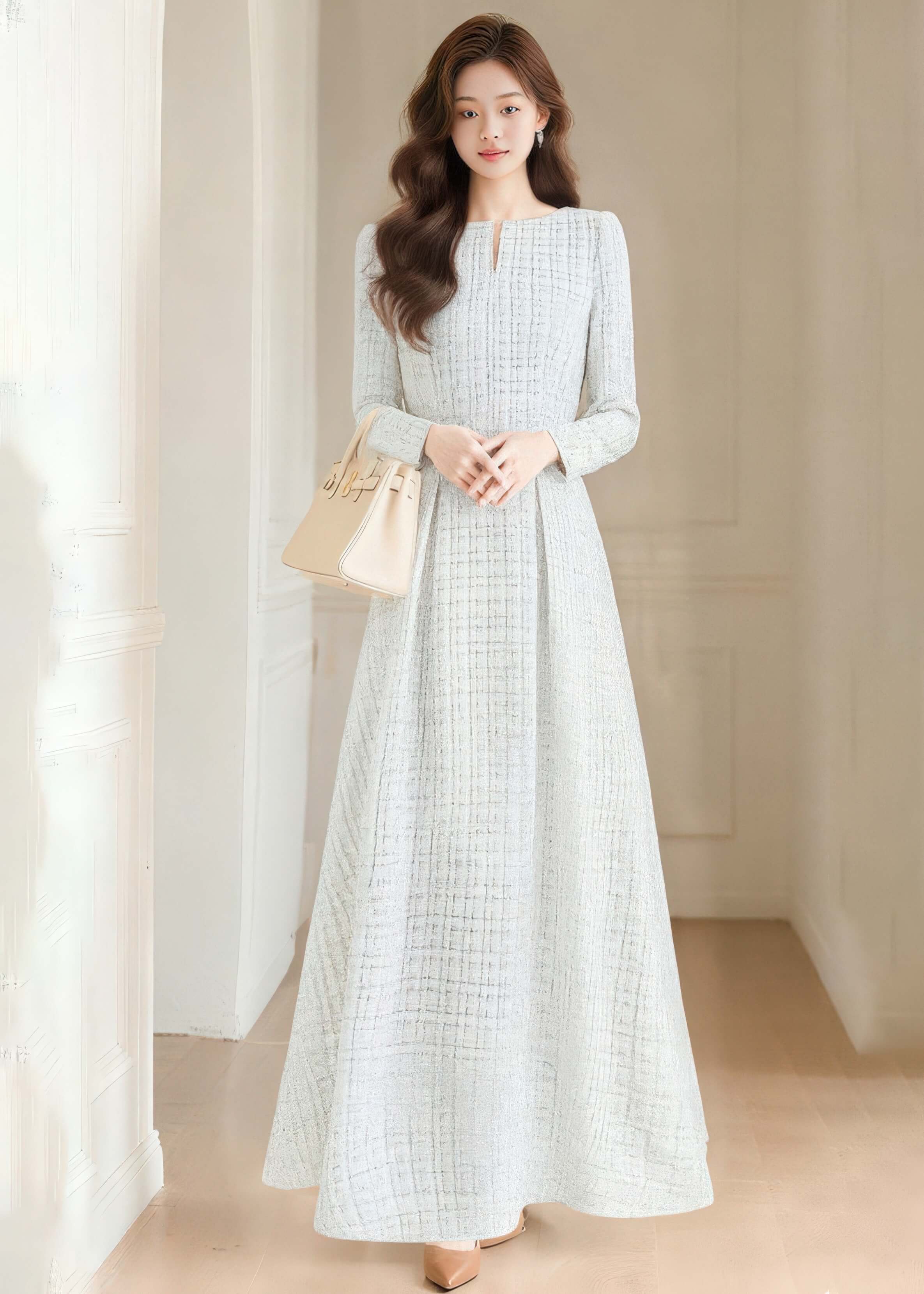 Full-length front view of a model wearing the Vivian Seven white tweed maxi dress with long sleeves and an A-line skirt, paired with a beige handbag.