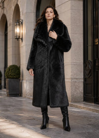 Full-length front view of model posing in a warm black longline faux fur coat featuring a wide notched collar