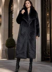 Front view of model adjusting the oversized wide lapel collar of a luxury longline black faux fur coat