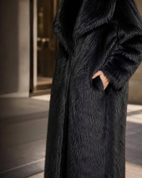 Close-up detail of side pocket and soft hairy texture on a women's longline black faux fur coat