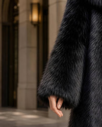 Close-up view of sleeve cuff showing the fluffy texture and premium quality of a black faux fur jacket
