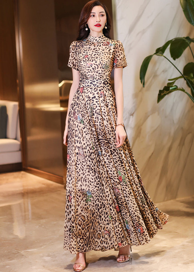 Detailed view of a woman in a luxury leopard print maxi dress standing in a modern indoor setting.
