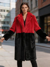 Model in a red and black bold statement colorblock faux fur long coat with arms slightly outstretched outdoors.
