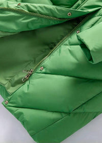 A close-up of a bright green puffer jacket showing the quilted stitching, a zipper closure, and metal snap buttons against a light background.