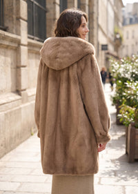Rear three-quarter perspective highlighting the gathered back drape, balloon sleeves, and relaxed hood of the taupe faux mink coat.   