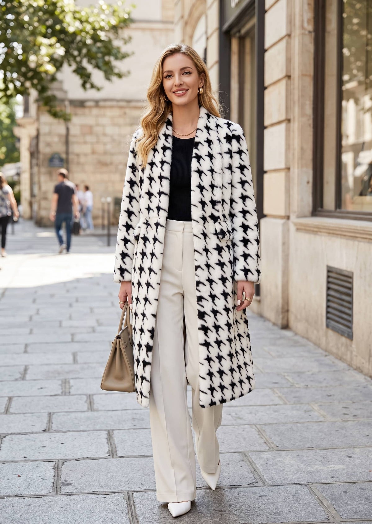 Elegant full-length front view of a woman wearing a tailored houndstooth faux fur winter coat with cream trousers and white heels.   