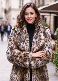 Close-up street portrait of a woman with crossed arms wearing a leopard faux fur midi coat with wide spread lapels.  