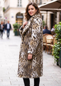 Three-quarter side perspective of a woman wearing a plush leopard faux fur midi coat highlighting sleeve and hem length.  
