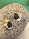 Pair of dangle earrings with multiple round, multi-colored disks resting on a large, rough grey stone.