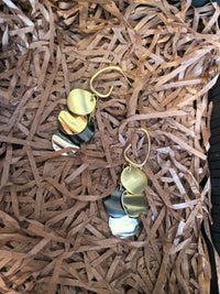 Pair of multi-colored disc dangle earrings lying on a bed of shredded brown paper packaging.