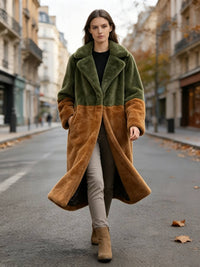 Model walking forward on a city street wearing an olive green and rust colorblock longline faux fur coat.