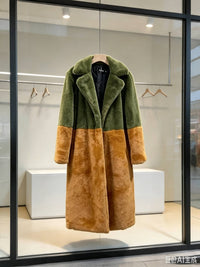 Olive green and rust brown colorblock faux fur long coat displayed on a wooden hanger in a store window.