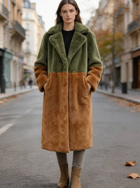 Full-length front view of a model in an olive and rust colorblock plush faux fur coat with hands in pockets.