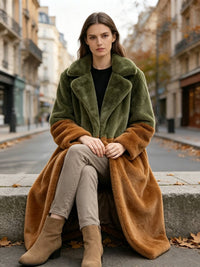  Woman seated on a stone ledge wearing an olive green and rust colorblock notch lapel faux fur coat.
