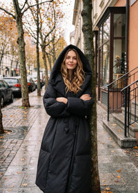 Vivian Seven black oversized wrap down coat with large hood worn up, street style view