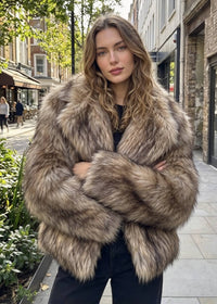 Front-facing view of a woman with crossed arms highlighting the fluffy shaggy faux fur texture and wide collar lapels.   