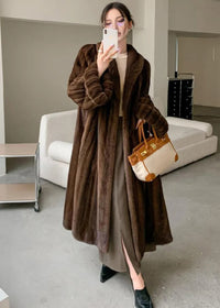 A mirror selfie of the woman wearing the brown faux fur coat. The image highlights the voluminous, ribbed texture of the sleeves and the oversized fit.