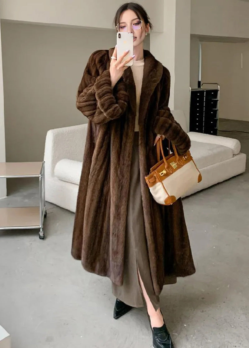 A mirror selfie of the woman wearing the brown faux fur coat. The image highlights the voluminous, ribbed texture of the sleeves and the oversized fit.
