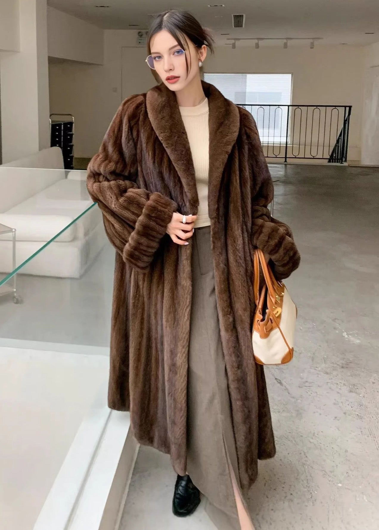 A slightly angled full-body shot of the woman posing in the brown faux fur coat, showcasing the drape of the garment and the wide shawl lapels.