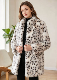 Front-facing indoor look of a woman lightly holding the front edges of a snow leopard print faux mink mid-length coat.   