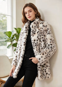 Three-quarter indoor fashion pose of a woman with hand in pocket modeling a snow leopard faux mink winter coat. 